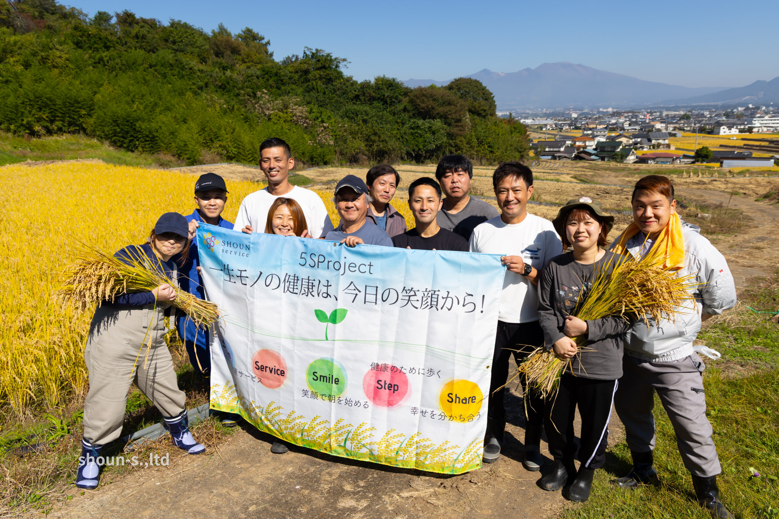 5月の爽やかな土の中で田植え体験を楽しむ商運サービスの社員たち